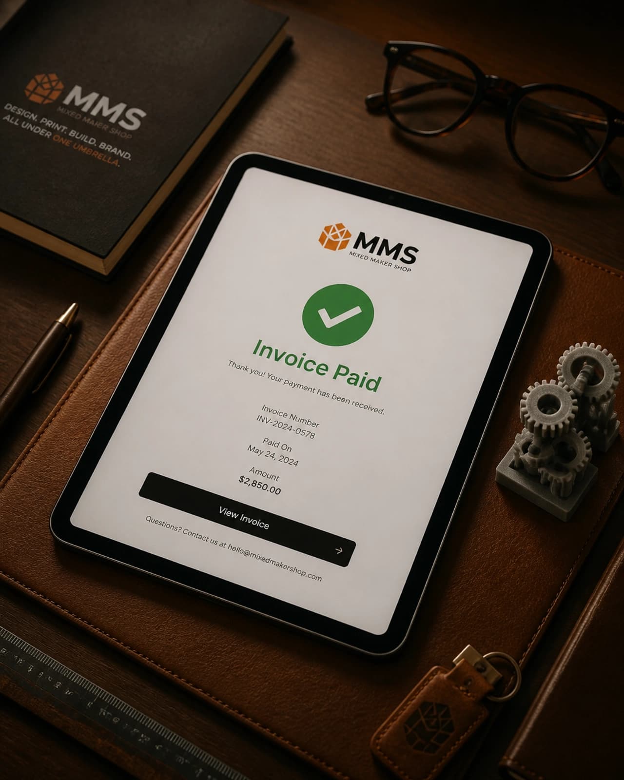 A digital tablet showing an Invoice Paid confirmation on a clean, professional desk